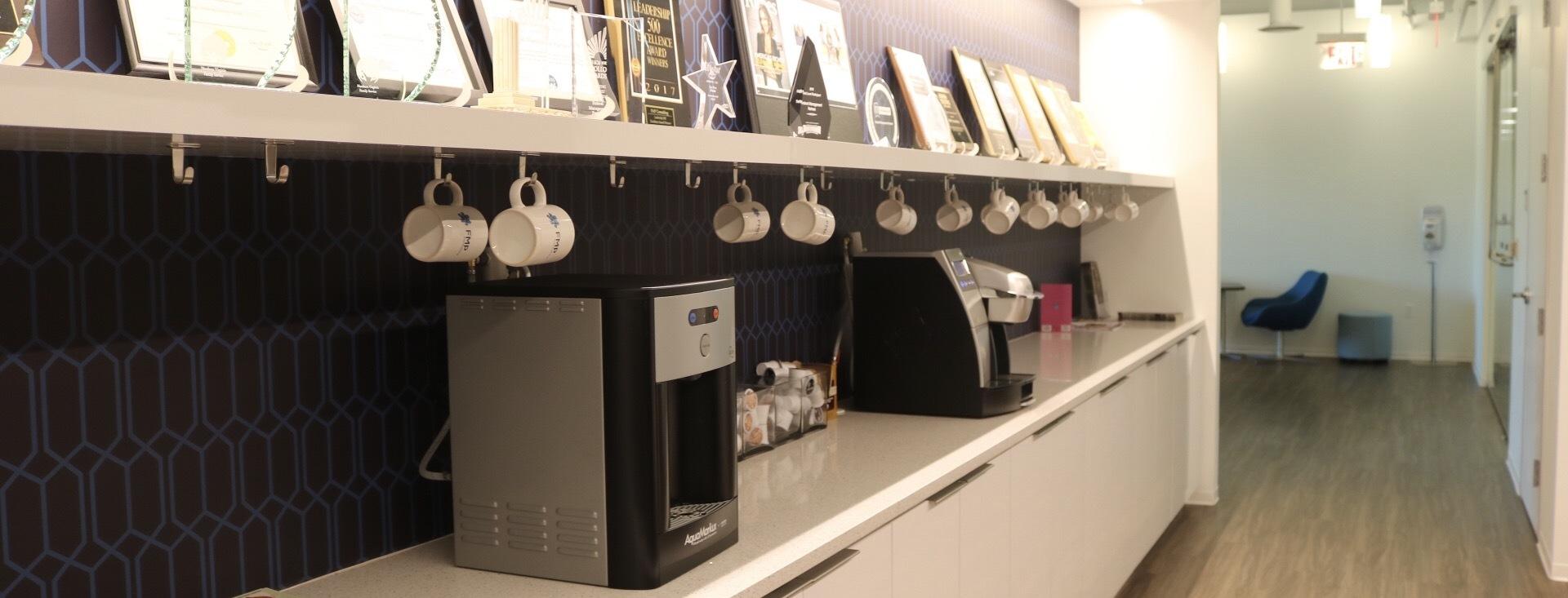 Photo of FMP office space, focusing on keurigs and coffee mugs