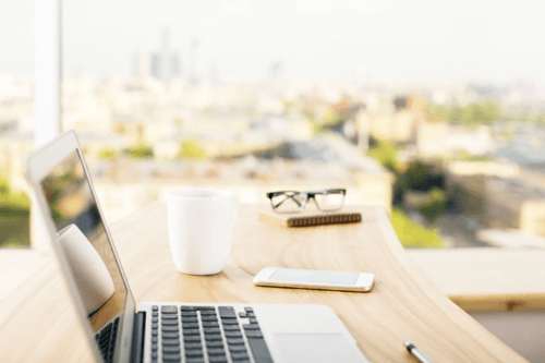 Photo of typical remote work station with laptop and coffee mug