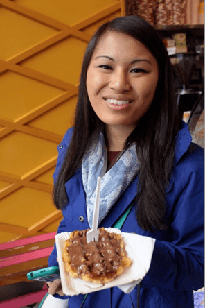 A Caitlin holding a Belgian Waffle in a cafe in Amsterdam.