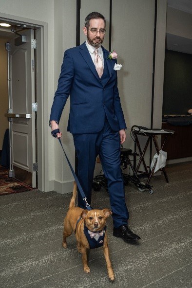 David in a suit walking a dog on a leash.