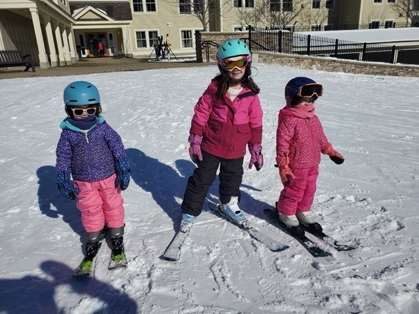 Three children wearing skis in the snow.