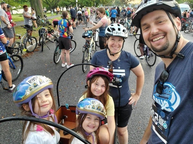 Justin and his family posing around their cargo bike, among other bikers.
