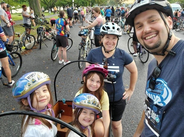 Justin and his family posing around their cargo bike, among other bikers.